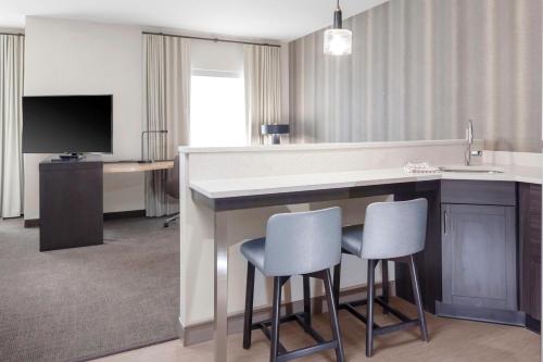 a hotel room with a bar with two chairs and a television at Residence Inn by Marriott St. Louis West County in Saint Louis