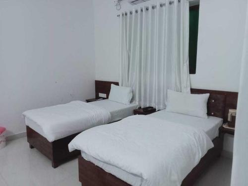 two beds in a hotel room with white sheets at OYO Hotel HR International Restaurant 