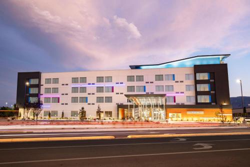 a large white building with purple lights in front of a street at Aloft by Marriott Reno Tahoe International Airport in Reno