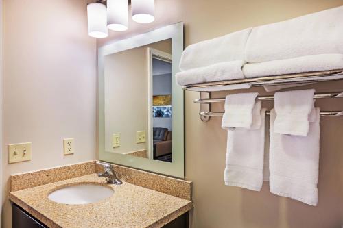 a bathroom with a sink and a mirror and towels at TownePlace Suites by Marriott Tulsa North/Owasso in Owasso