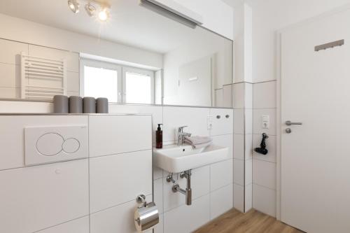 a white bathroom with a sink and a mirror at Wohnung Bontje in Juist