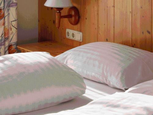 2 almohadas sentadas en una cama junto a una lámpara en Sportpension Aichholzer, en Oberaichwald