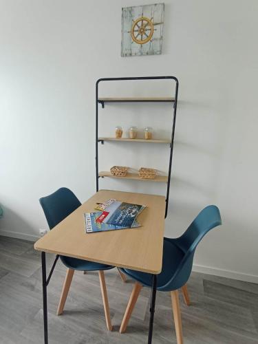 une table et deux chaises avec un magazine dessus dans l'établissement LE KENAV - STUDIO A 300 M DU PORT, à Locmiquélic