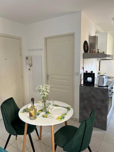 une cuisine avec une table avec des chaises vertes et une table avec des fleurs dans l'établissement charmant studio à Menton, à Menton