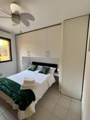 - une chambre avec un lit doté d'oreillers verts et d'un ventilateur de plafond dans l'établissement charmant studio à Menton, à Menton