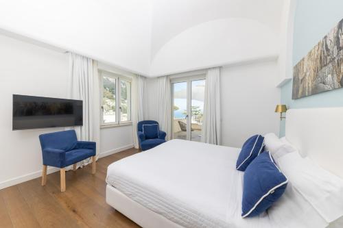 een slaapkamer met een bed en twee blauwe stoelen bij Casa Dani Capri in Capri