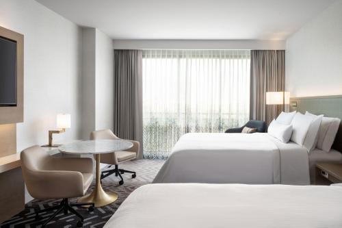 a hotel room with two beds and a desk at The Westin Anaheim Resort in Anaheim