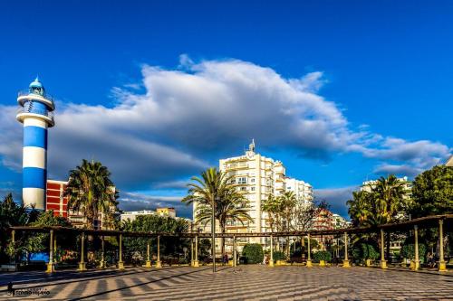 a lighthouse and a building with a blue and white at Apartamentos Turisticos Las Yucas in Torre del Mar