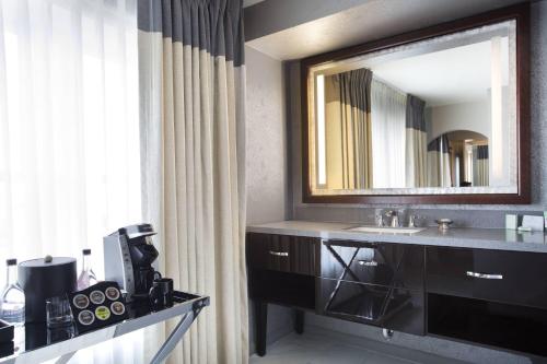 a bathroom with a sink and a mirror at Ambassador Hotel Tulsa, Autograph Collection in Tulsa