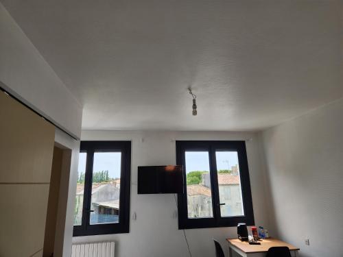 Cette chambre dispose de 2 fenêtres et d'une télévision murale. dans l'établissement Chambre privée indépendante, à Chenac-sur-Gironde