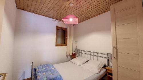 een kleine slaapkamer met een bed en een roze licht bij Schuss 6 appartement 4 pax au pied des pistes in Saint-Jean-dʼAulps