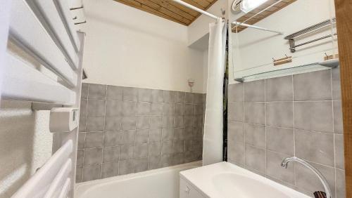 une salle de bain avec une baignoire blanche et un lavabo dans l'établissement Schuss 6 appartement 4 pax au pied des pistes, à Saint-Jean-dʼAulps