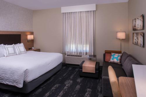 TownePlace Suites by Marriott Saskatoon في ساسكاتون: غرفه فندقيه بسرير واريكه