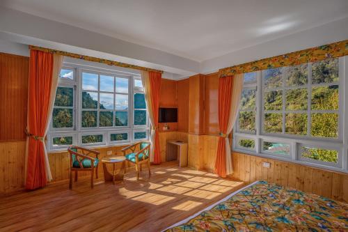 a bedroom with a table and two windows at Summit Gangchen Hotel in Lachen