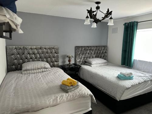 a bedroom with two beds with towels and a chandelier at 116 Maison Dieu Road Room D in Dover in Kent
