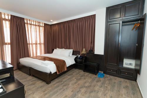 a hotel room with a bed and a dresser at Queen Central Hotel - Ben Thanh Market in Ho Chi Minh City