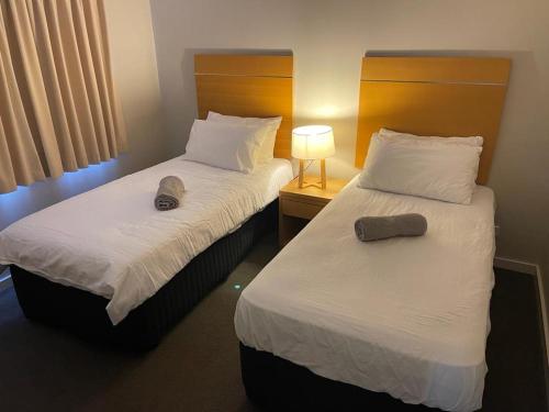 2 camas en una habitación de hotel con lámpara y toallas en Tranquility in the Swan Valley en The Vines