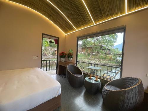 a bedroom with a bed and two chairs and a window at Sapa Bamboo Eco in Sa Pa