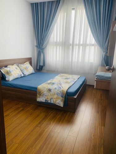 a bedroom with a bed and a window with blue curtains at Căn hộ Quy Nhơn-du lịch giá rẻ 5 in Quy Nhon