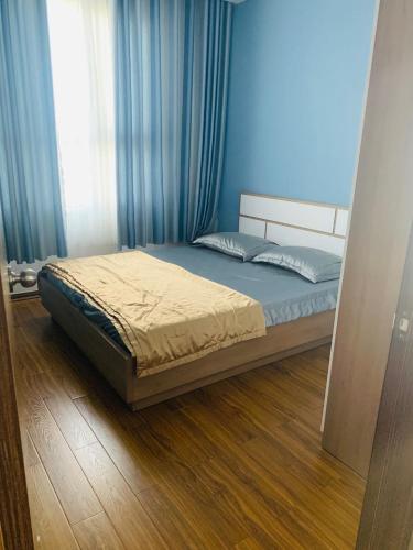 um quarto com uma cama com cortinas azuis e piso em madeira em Căn hộ Quy Nhơn-du lịch giá rẻ 5 em Quy Nhon
