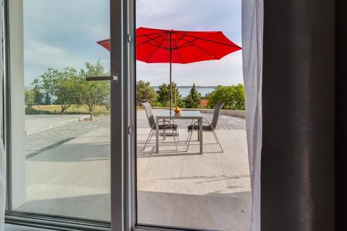 a table and chairs with a red umbrella on a patio at Villa Stjepanovic in Tribanj-Krušćica