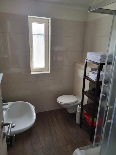 a bathroom with a sink and a toilet and a window at Apartments Alen in Umag