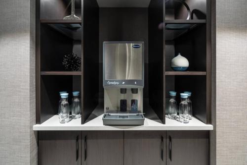 a coffeemaker on a shelf with bottles and glasses at AC Hotel by Marriott Portsmouth Downtown/Waterfront in Portsmouth