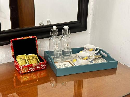 a tray with two bottles and cups on a table at 19th Century Boutique Hotel in Melaka