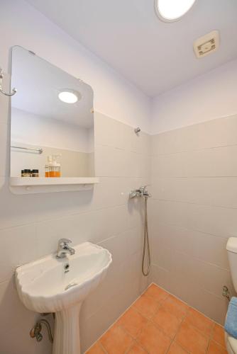 a white bathroom with a sink and a mirror at Hermes Rooms in Tinos