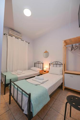 a bedroom with two beds and a table and a chair at Hermes Rooms in Tinos