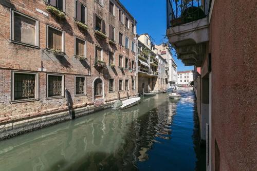 a canal between two buildings with boats in the water at Behind On The Canalside Venice in Venice
