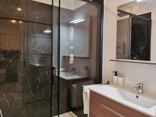 a bathroom with a glass shower and a sink at Appart Hotel Spa Perpignan in Perpignan