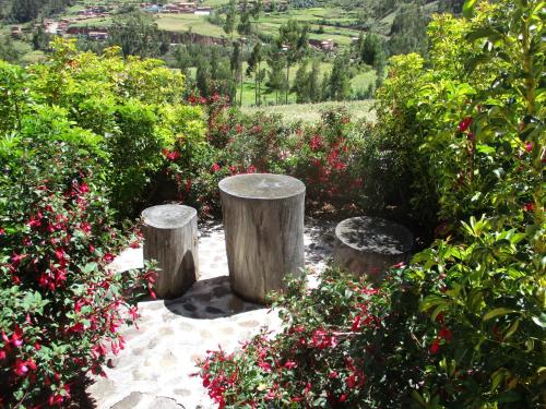 a garden with three logs and some flowers and trees at Casa de Oren in Pisac