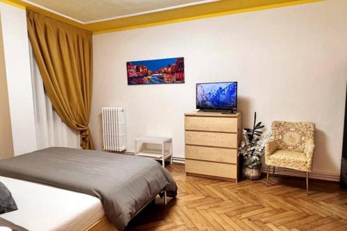 1 dormitorio con 1 cama, TV y silla en Behind On The Canalside Venice, en Venecia