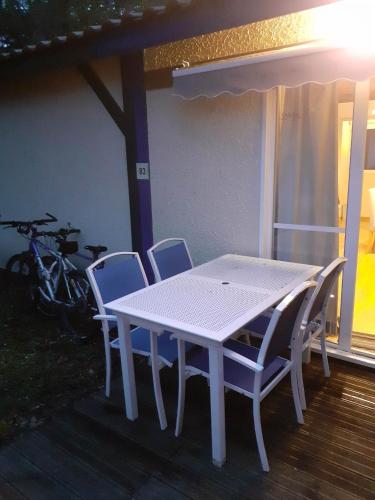 une table et des chaises blanches sur une terrasse dans l'établissement Maisonnette à Vieux-Boucau, à Soustons