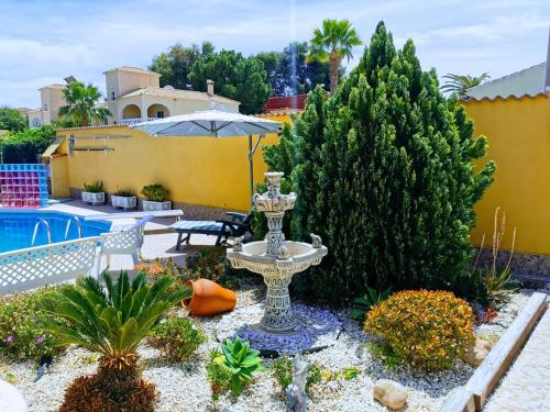une fontaine dans un jardin à côté d'une piscine dans l'établissement Villa SIA, à Torrevieja