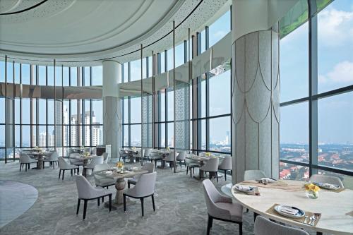 a restaurant with tables and chairs and large windows at The Westin Surabaya in Surabaya