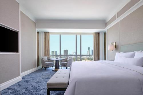 a hotel room with a bed and a table with chairs at The Westin Surabaya in Surabaya