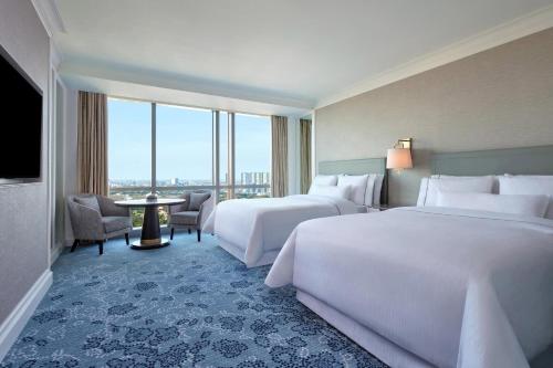 a hotel room with two beds and a large window at The Westin Surabaya in Surabaya
