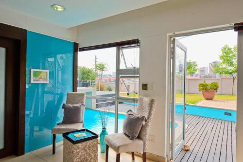 a living room with two chairs and a swimming pool at Protea Hotel by Marriott Windhoek Furstenhof in Windhoek