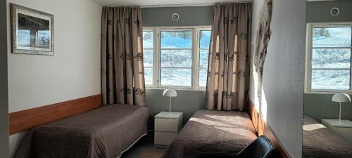 a small bedroom with two beds and two windows at Fishing Lodge Hálsakot in Sleðbrjótur