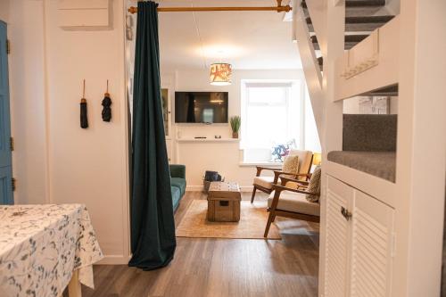 a small room with a staircase and a living room at Sandals cottage in St Ives