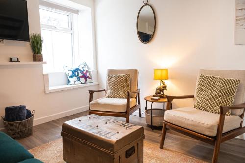 a living room with chairs and a table and a mirror at Sandals cottage in St Ives