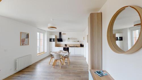 - une cuisine et une salle à manger avec une table et un miroir dans l'établissement Appartement Les Sables d’Or, à Barneville-Carteret