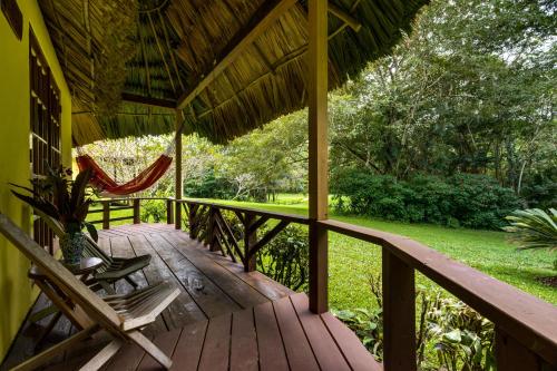 a porch of a house with a hammock and chairs at Tanager RainForest Lodge in Big Falls