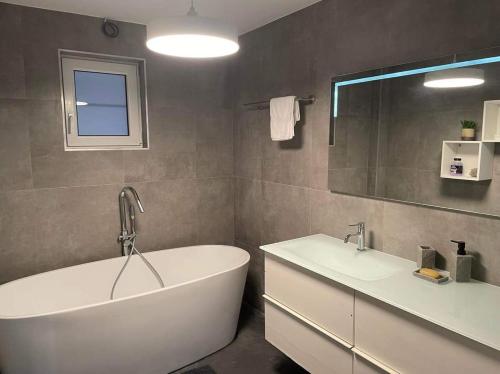 uma casa de banho com uma banheira branca e 2 lavatórios em Guest House and swimming pool em Romsée