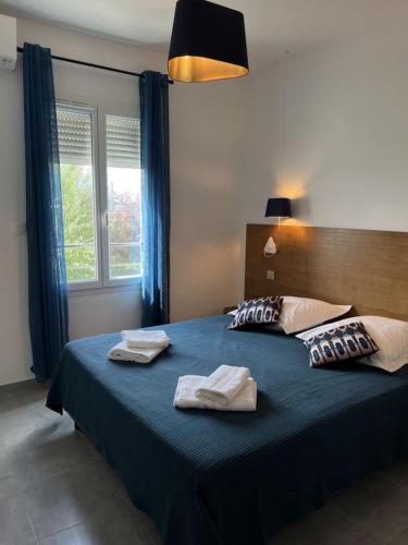 une chambre avec un lit bleu avec deux serviettes dessus dans l'établissement Villa de Vinci Locasete, à Sète