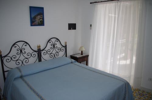 a bedroom with a bed with a blue blanket and a window at Casa Fortunata in Positano