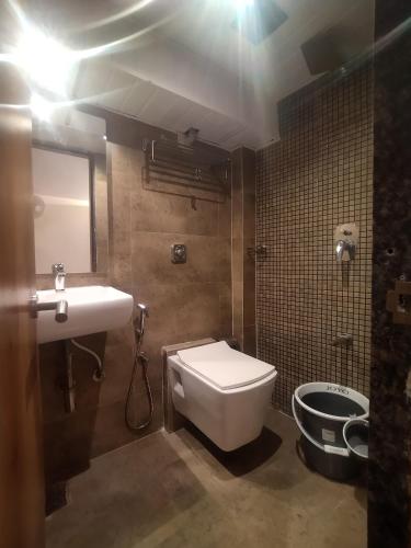 a bathroom with a white toilet and a sink at Hotel Kishan Lodging & Boarding in Mumbai