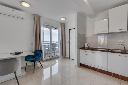 a kitchen with white cabinets and a table with a blue chair at Villa Stjepanovic in Tribanj-Krušćica